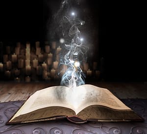 Fantasy scene: an open book in front of lit candles releases a glowing energy