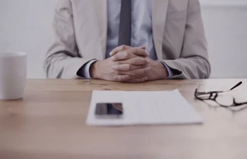 man with hands folded during job interview