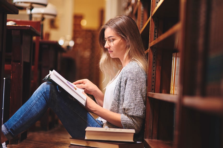 female-student-reading-and-sitting-on-library-floor-2